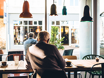 Older man sitting at a table enjoying his coffee