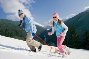 Young people sledding with sunglasses on