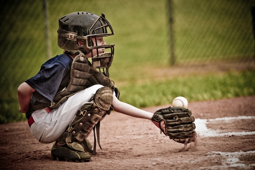 Boy playing catcher position in baseball game