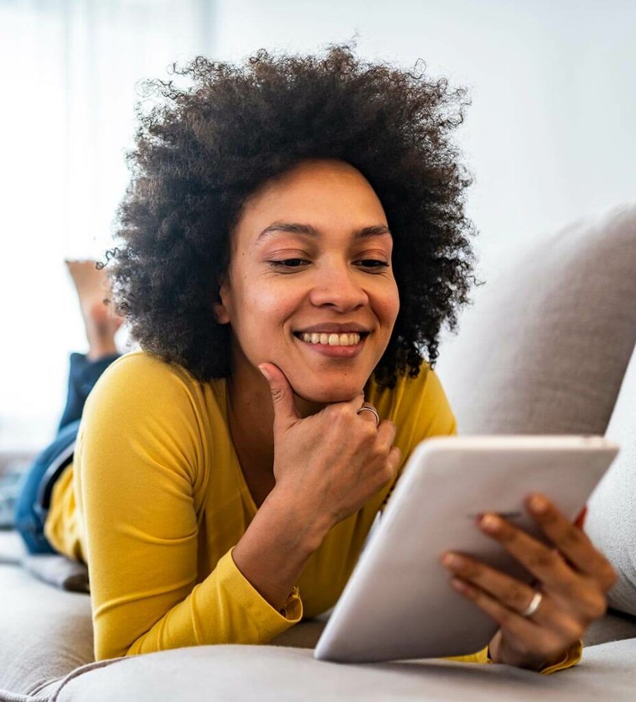 Woman Laying on a Couch Looking at Her Tablet Computer